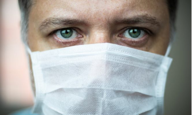 closeup-middleaged-greeneyed-doctor-with-mask-on-his-face-picture-id1215484559-666x399